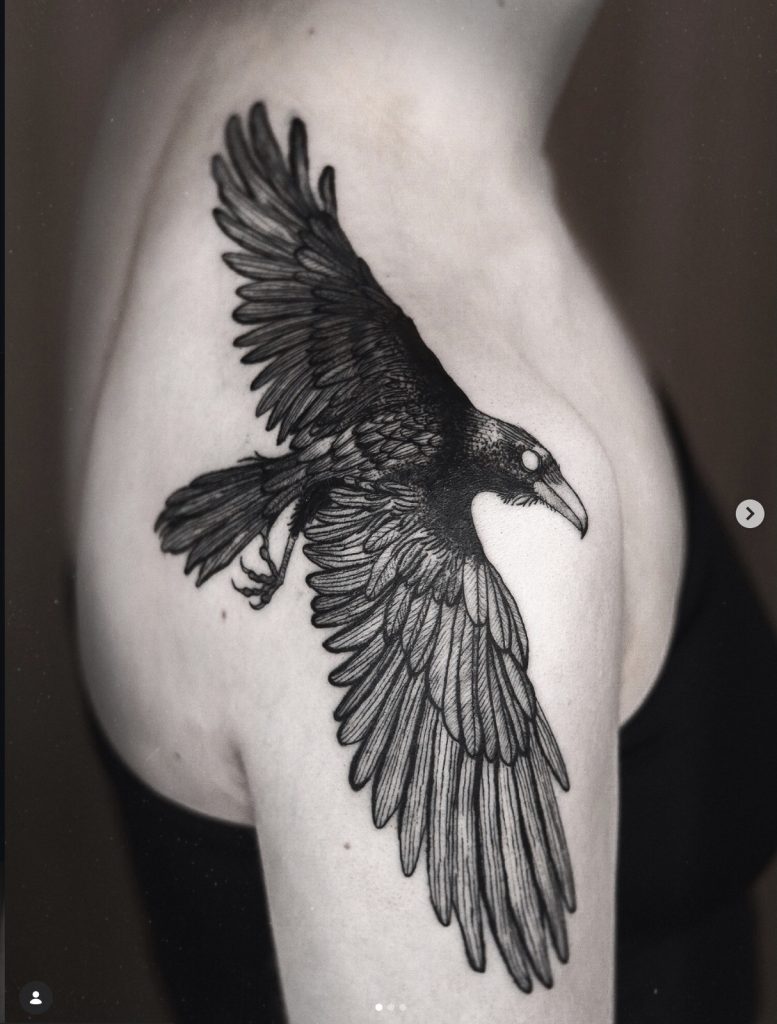 Blackwork-tattoo van een vliegende raaf op de schouder, door Mara.