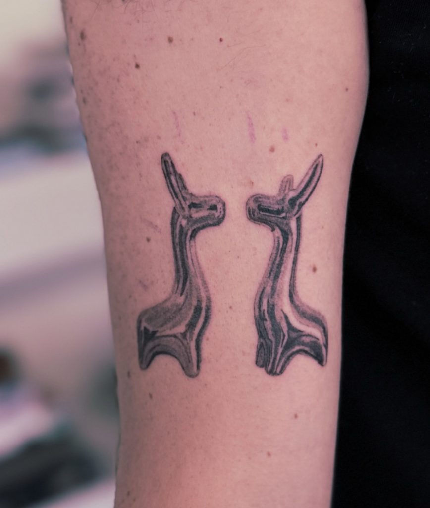 Tattoo van twee gespiegelde, gestileerde dierfiguren, door Mitchel.