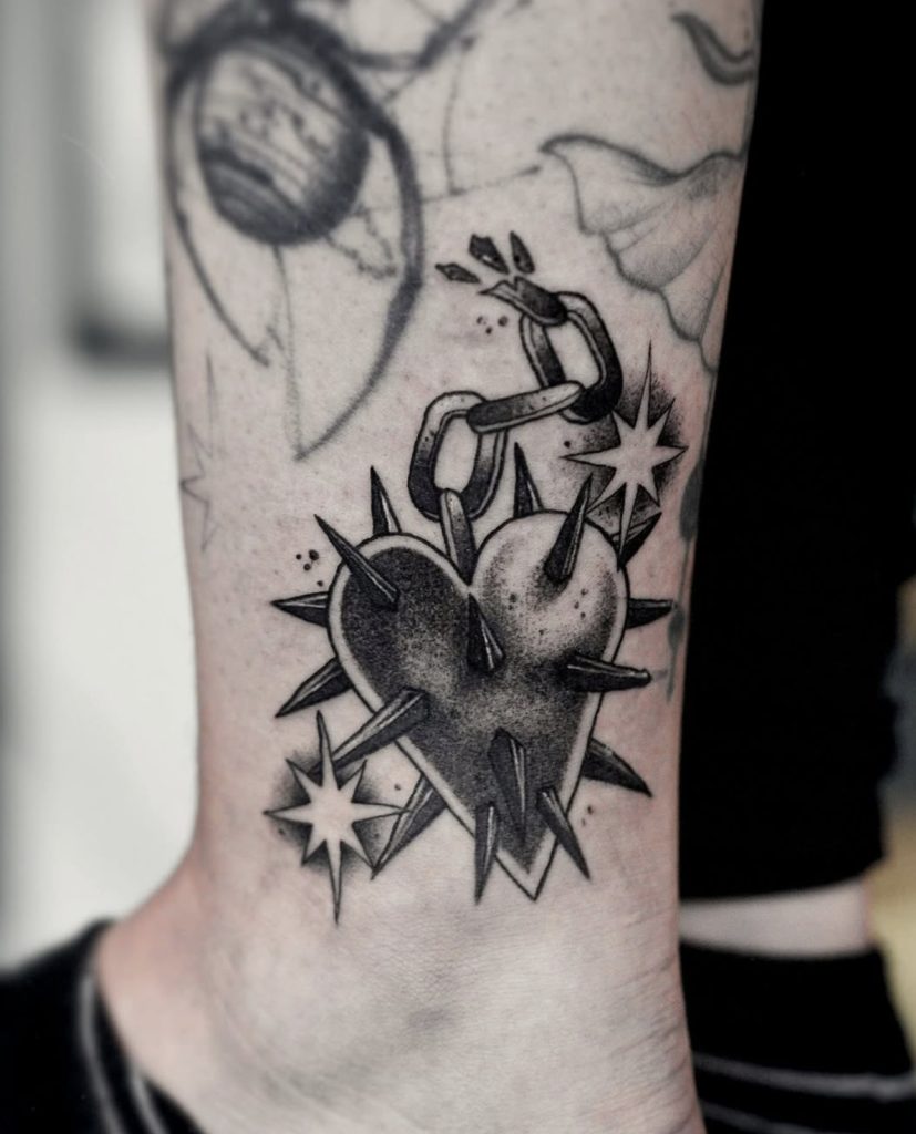 Blackwork-tattoo van een hart met stekels, haak en sterren, door Sonja.