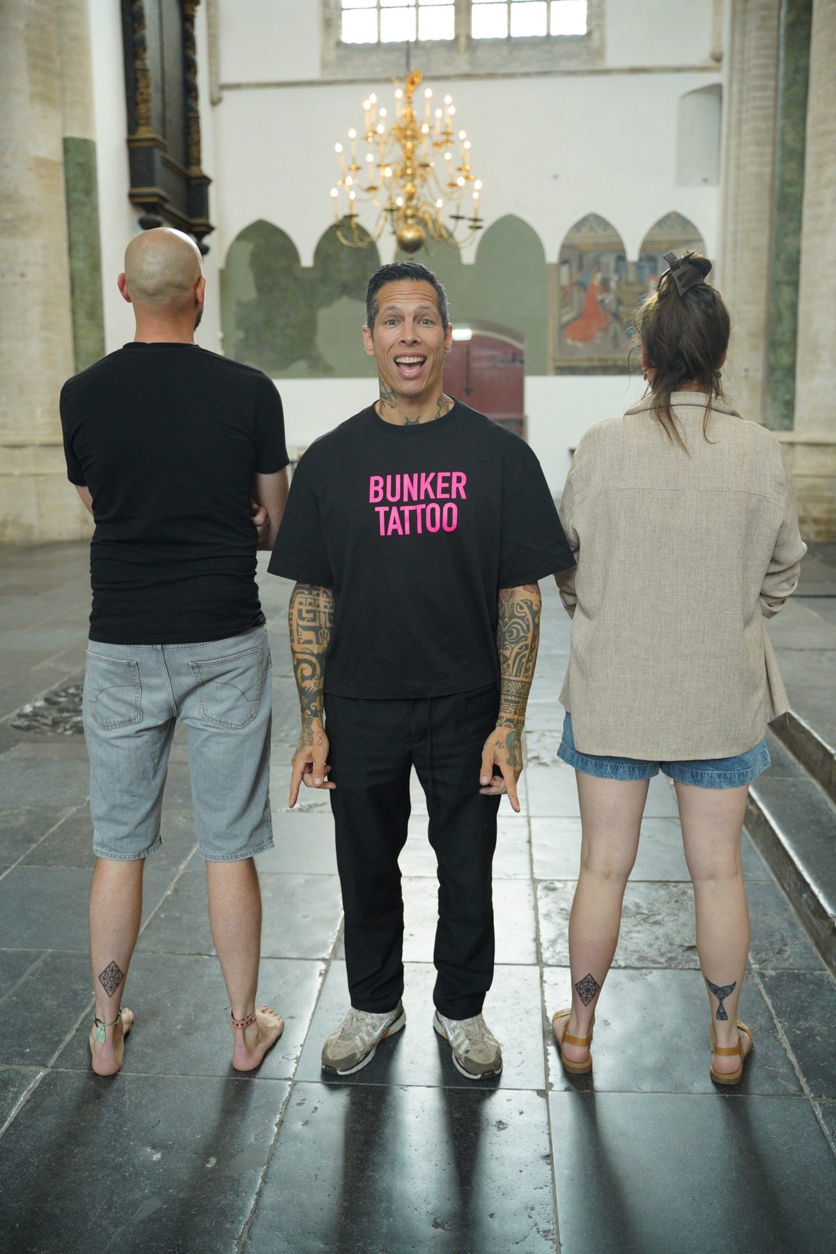 Manon and Vincent showing their tattoos alongside Roger at the Grote Kerk