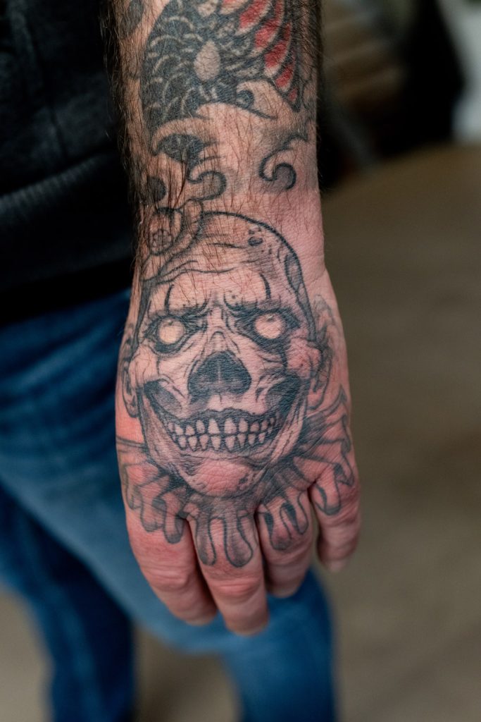 Schedeltattoo met zwarte lijnen en grijze schaduw op de handrug, door Roger.