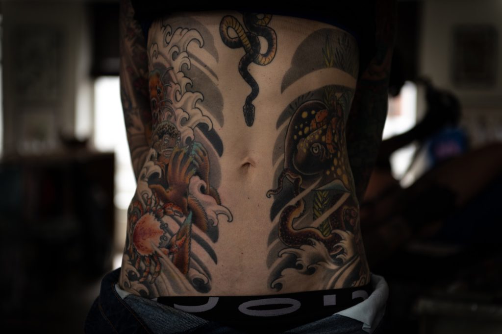 Lucie’s stomach tattoo with animals, leaves and waves.