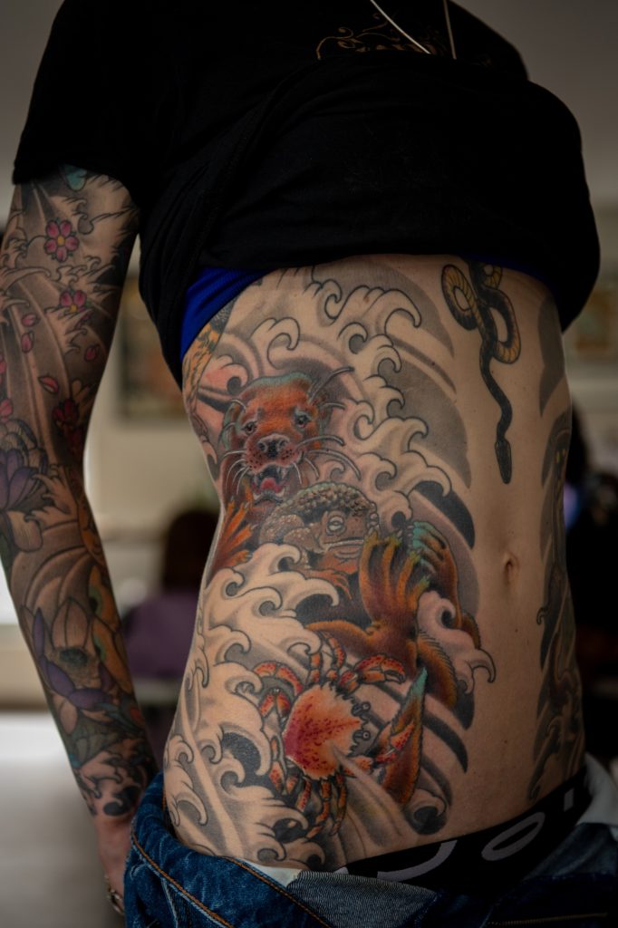 Lucie’s side tattoo with animals, a crab, a snake and waves.